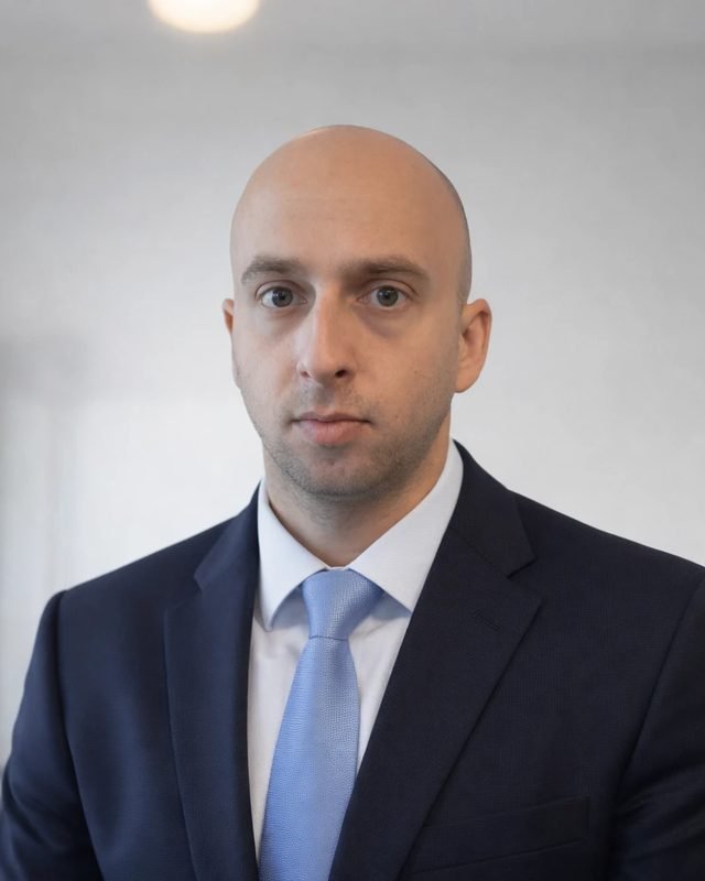 Portrait of Omri Moskovitch, founder of Desert Force & Co., in a dark suit and light blue tie.